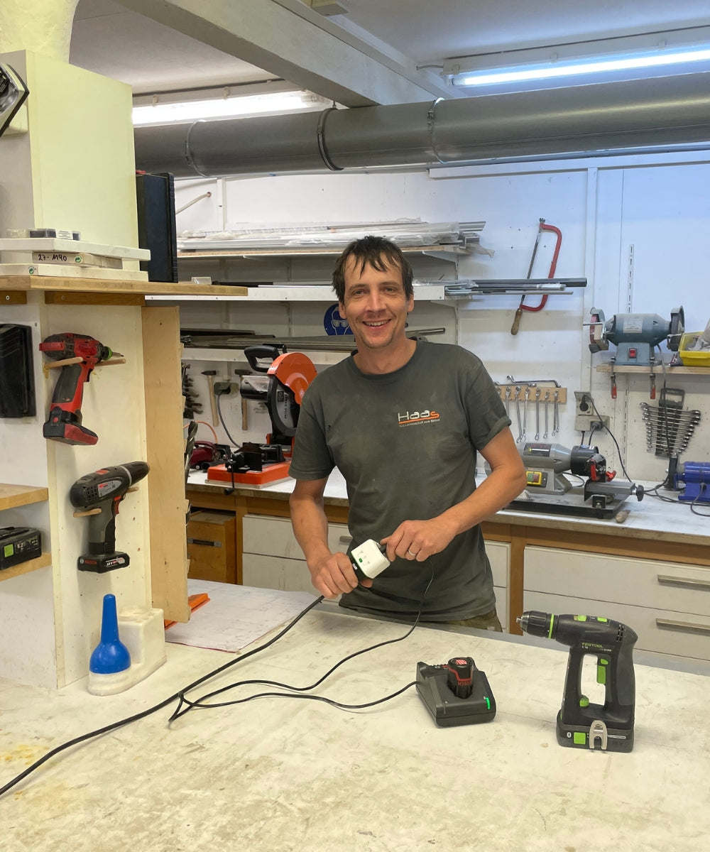 Schreiner lädt Akkuschrauber mit dem Akku Life Guard in der Werkstatt – sichere Ladung nach Feierabend