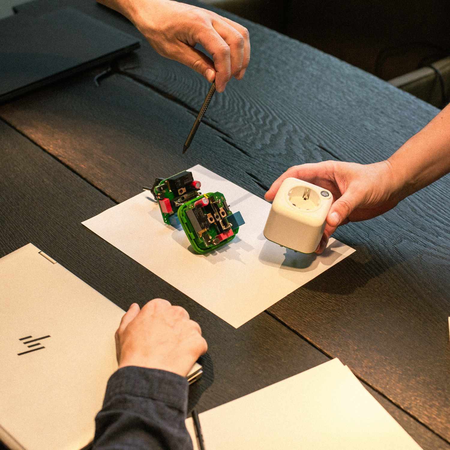 Entwicklerteam bespricht Akku Life Guard am Tisch, technische Details und Bauteile sichtbar