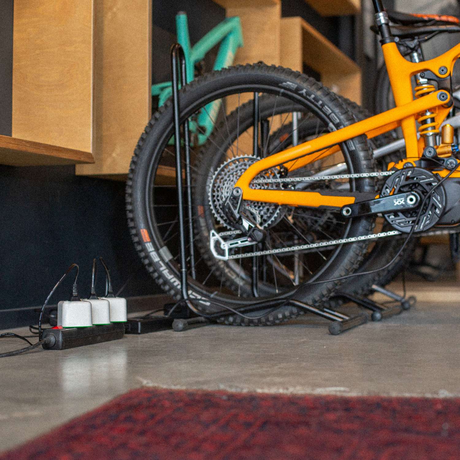 Orangefarbenes E-Bike im Fahrradladen angeschlossen an Akku Life Guard, smarte Ladeinfrastruktur für mehrere Räder
