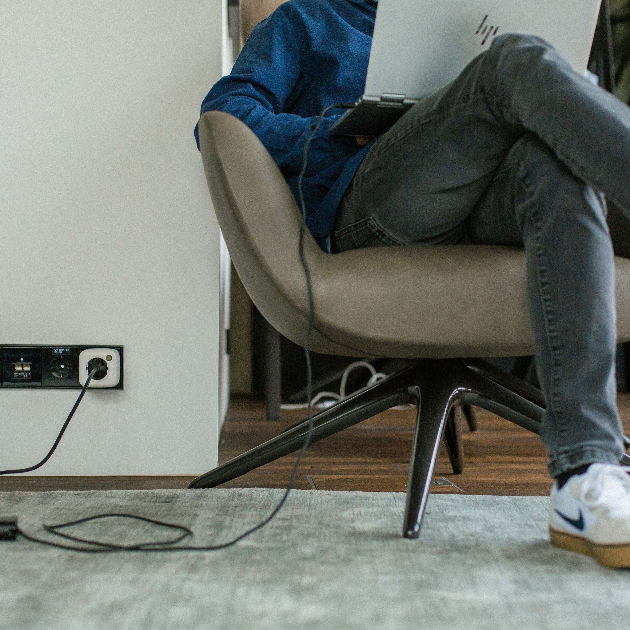 Person sitzt auf Stuhl mit Laptop, Akku Life Guard schützt angeschlossene Geräte beim Laden